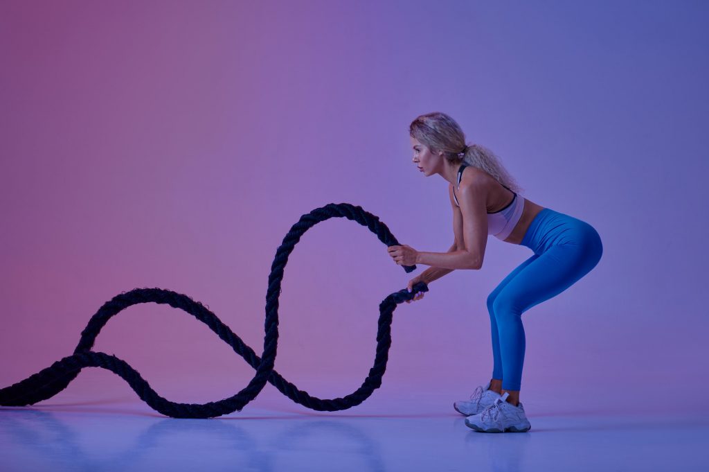 Young sportswoman with ropes in studio, crossfit
