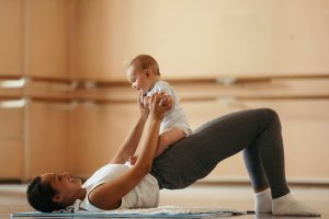 Happy mother working out with her baby in a health club.